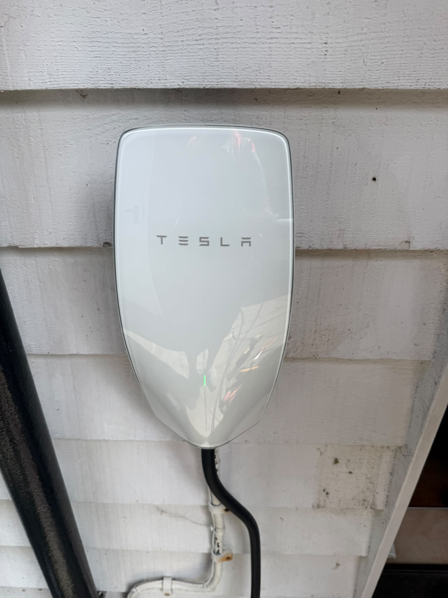 Tesla electric vehicle charger installed on a dark exterior wall